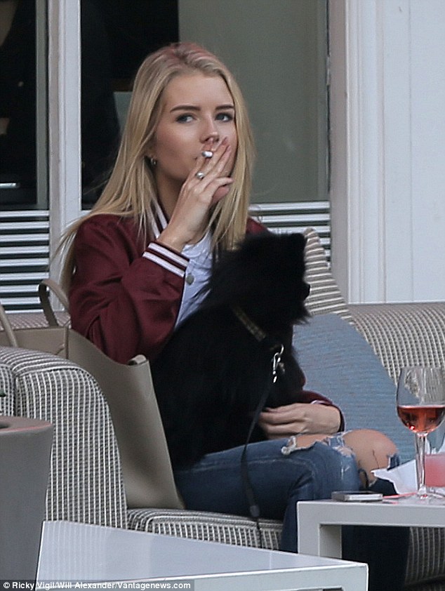 Like sister, like sister: The 18-year-old superstar sibling looked typically trendy in a chic bomber jacket and ripped jeans as she sat outside the eatery puffing on a cigarette